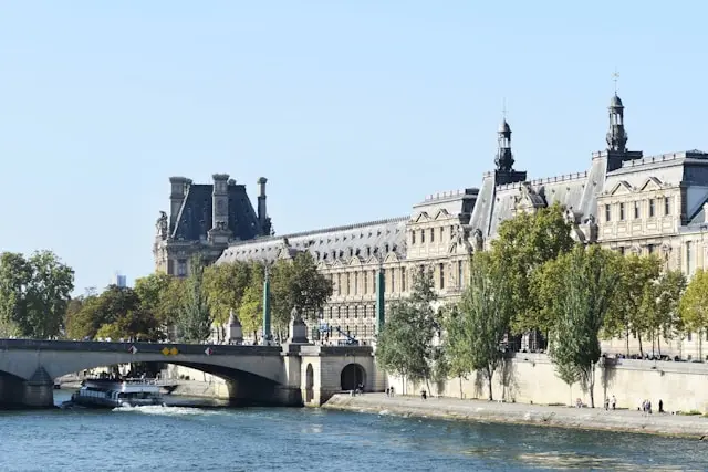 Daytime view of the Louvre and Pont du Carrousel along the Seine River in Paris
